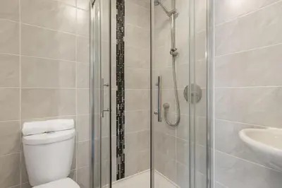 a bathroom with a shower and a toilet and a sink at Rosevilla Farmhouse in Portreath