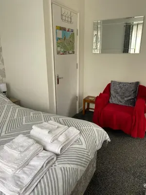 a bedroom with a bed and a red chair at 24trenance in Newquay