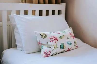 a bed with white pillows and a pillow with fish at Maen Lay, Gorran Haven in Gorran Haven