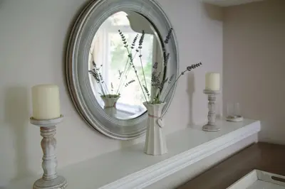 a mirror on a mantle with a vase and candles at Maen Lay, Gorran Haven in Gorran Haven
