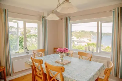 a dining room with a table and chairs and windows at Maen Lay, Gorran Haven in Gorran Haven