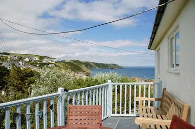 a balcony with two benches and a view of the ocean at Maen Lay, Gorran Haven in Gorran Haven
