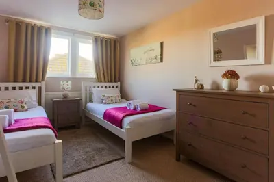a small bedroom with two beds and a dresser at Maen Lay, Gorran Haven in Gorran Haven