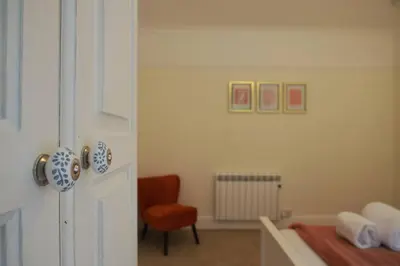 a room with a bed and a chair and a door at Oakroyd in Gorran Haven