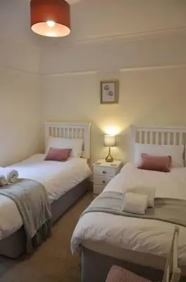 a bedroom with two beds and a lamp in it at Oakroyd in Gorran Haven