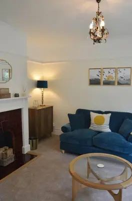 a living room with a blue couch and a fireplace at Oakroyd in Gorran Haven