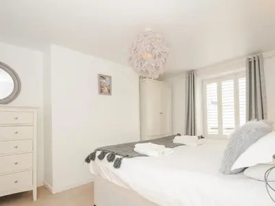 a white bedroom with a bed and a chandelier at Quay House in St Austell