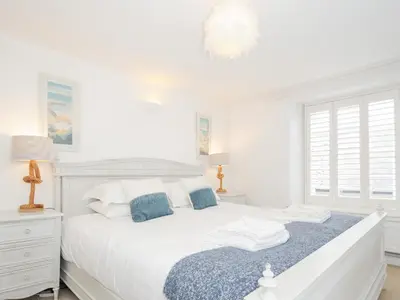 a white bedroom with a white bed and a blue blanket at Quay House in St Austell