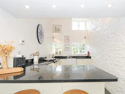 a white kitchen with a clock on the wall at Quay House in St Austell
