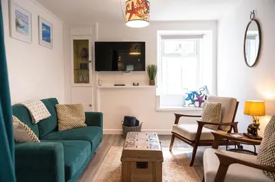 a living room with a green couch and a table at Sandals cottage in St Ives