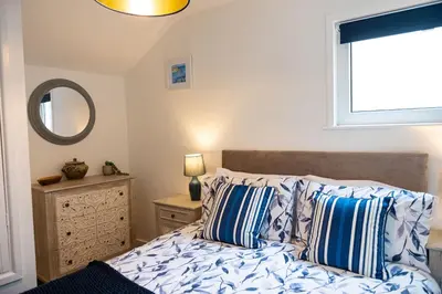 a bedroom with a bed with blue and white pillows at Sandals cottage in St Ives