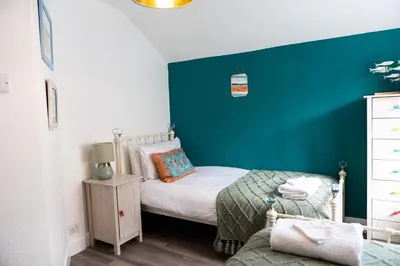 a small bedroom with a green accent wall at Sandals cottage in St Ives