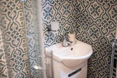 a bathroom with a white sink and a shower at Sandals cottage in St Ives