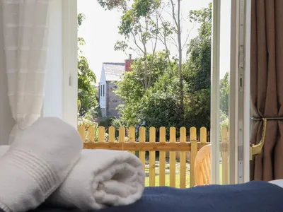 a room with a door open to a porch with a fence at The Forge in Falmouth