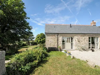 a stone cottage with a grassy yard in front of it at The Forge in Falmouth
