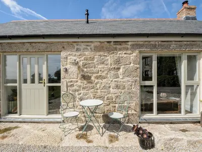 a stone house with two chairs and a table at The Forge in Falmouth