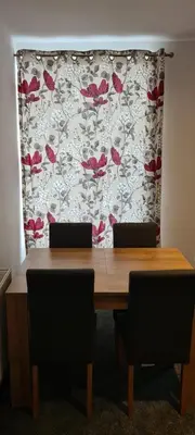 a table with two chairs and a curtain with red flowers at Fore Street Bodmin in Bodmin