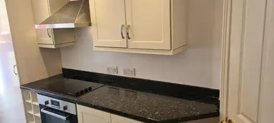 a kitchen with white cabinets and a black counter top at Fore Street Bodmin in Bodmin