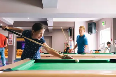 a young girl playing pool with a cue at Newquay Bay Resort 181 in Porth