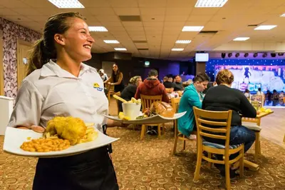 a woman is holding a plate of food at Newquay Bay Resort 181 in Porth