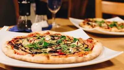 a pizza sitting on top of a white plate on a table at Newquay Bay Resort 181 in Porth