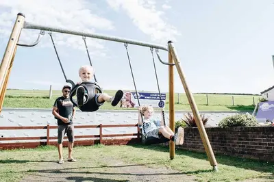 two boys are playing on a swing at Newquay Bay Resort 181 in Porth
