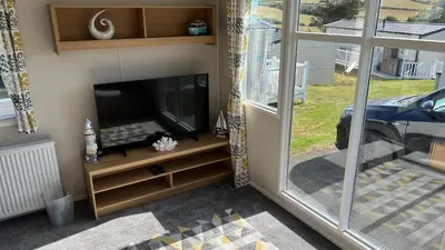 a flat screen tv sitting on a stand next to a window at Newquay Bay Resort 181 in Porth