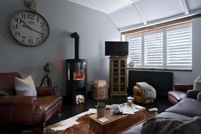 a living room with a couch and a clock on the wall at The Lambing Shed, Cornwall in Altarnun