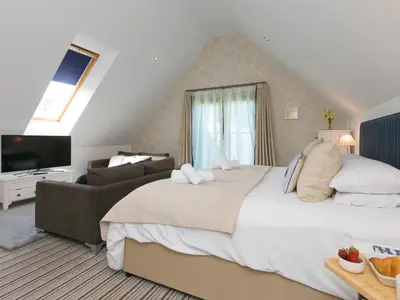 a bedroom with a large bed and a couch at Porthminster Penthouse in St Ives