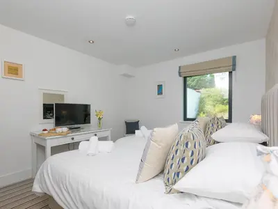 a bedroom with two beds and a desk with a television at Porthminster Penthouse in St Ives