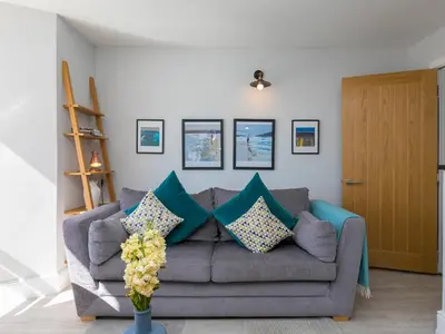a living room with a gray couch with blue pillows at Waters Watch in St Ives