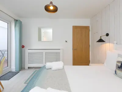 a white bedroom with a large bed and a window at Waters Watch in St Ives