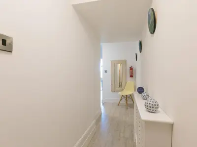 a white hallway with a table and a yellow chair at Waters Watch in St Ives