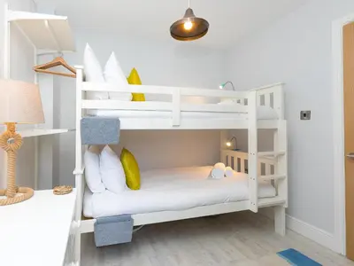 a white bunk bed in a room with a lamp at Waters Watch in St Ives