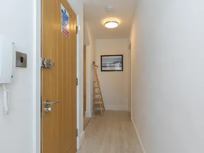 a hallway with a door and a ladder at Waters Watch in St Ives