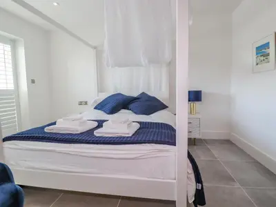 a white bed with blue pillows in a bedroom at 30 Cliff Edge in Newquay