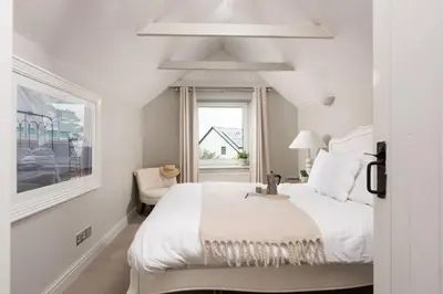 a white bedroom with a bed and a window at Spindrift, St Ives in St Ives