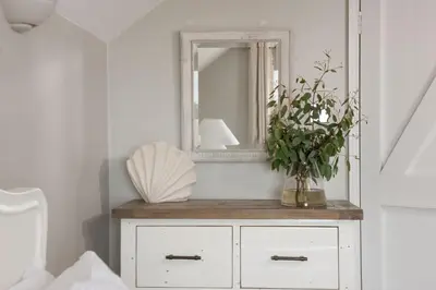 a white dresser with a mirror and a plant on it at Spindrift, St Ives in St Ives