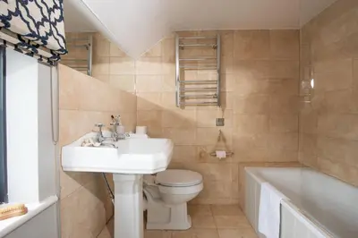 a bathroom with a sink and a toilet and a tub at Spindrift, St Ives in St Ives