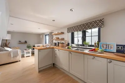 a kitchen with a sink and a living room at Spindrift, St Ives in St Ives
