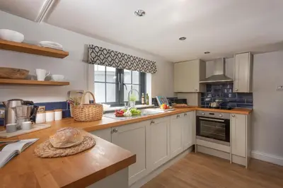 a kitchen with white cabinets and a counter top at Spindrift, St Ives in St Ives
