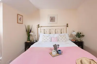 a bedroom with a pink bed with a tray on it at Pump Cottage in Gwithian