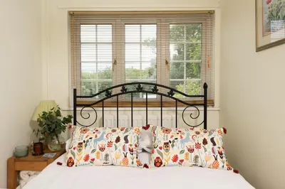 a bedroom with a bed with pillows and a window at Pump Cottage in Gwithian
