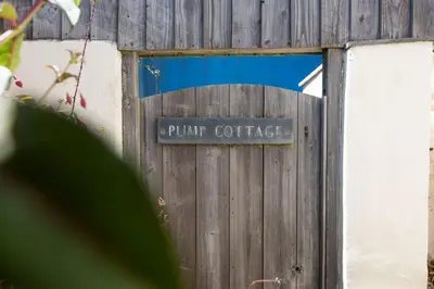 a wooden fence with a sign that reads pump coffee at Pump Cottage in Gwithian