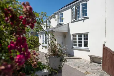 a white house with flowers in front of it at Pump Cottage in Gwithian