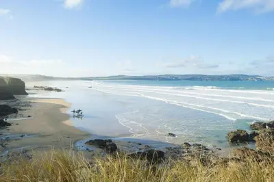 a beach with a group of people standing in the water at Pump Cottage in Gwithian