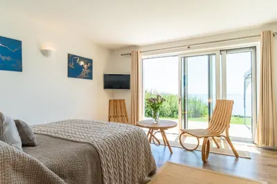 a bedroom with a bed and a table and a window at Finest Retreats - Avalon Sea Views in Downderry