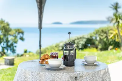 a table with two cups of coffee and pastries on it at Finest Retreats - Avalon Sea Views in Downderry