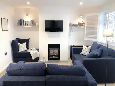 a living room with blue couches and a fire place at Suncroft in Port Isaac