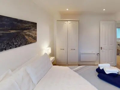 a bedroom with a white bed and a painting on the wall at Suncroft in Port Isaac